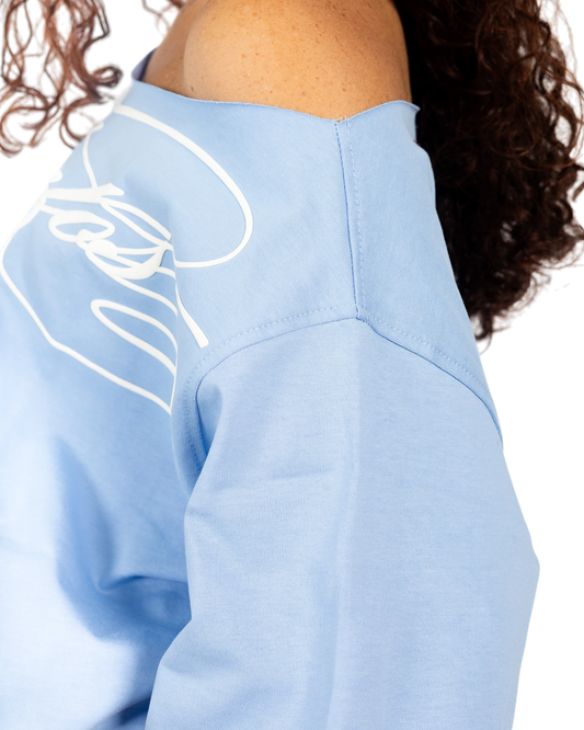 Anetos baby blue off-shoulder top with white graphic print on sleeve. Soft cotton blend.