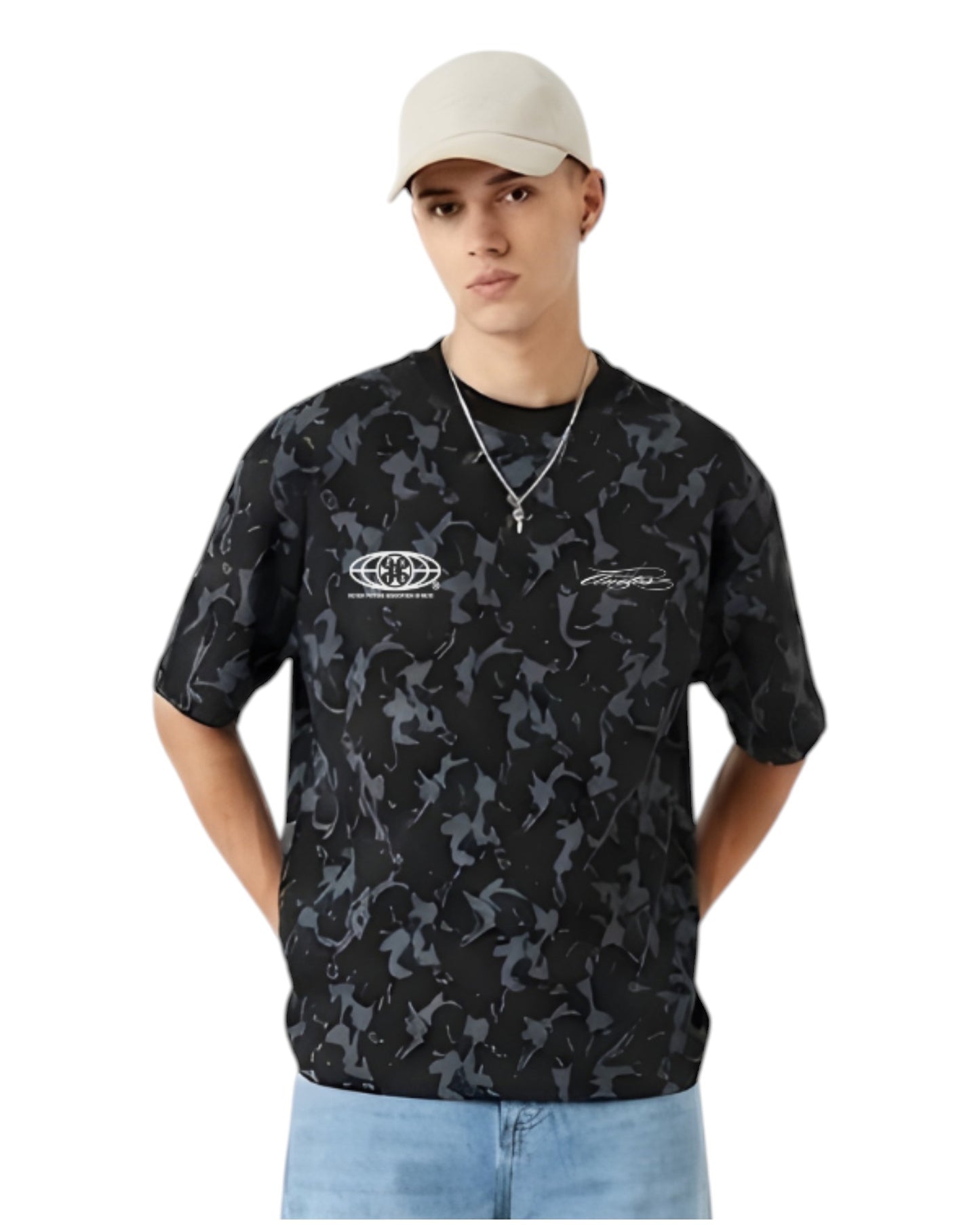 Anetos Blackout Camo Tee with a relaxed fit, featuring a black and grey camouflage pattern and short sleeves. Model wears light wash jeans and a beige cap.